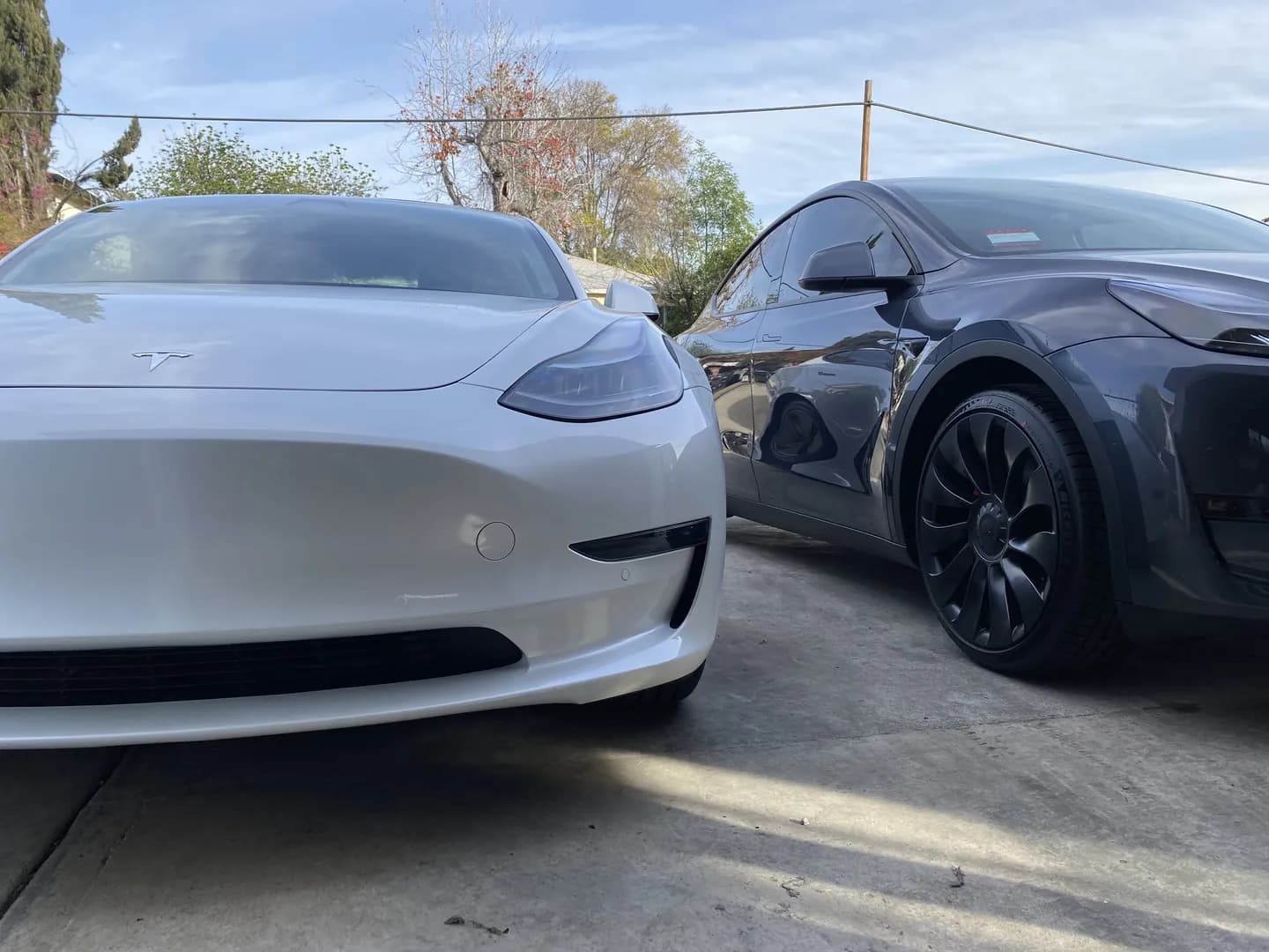 White Tesla Model 3 and grey Model Y nose to nose in a client's driveway