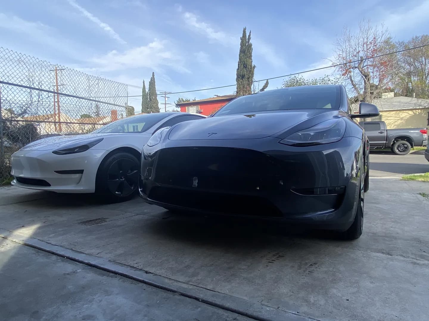 White and grey Tesla freshly detailed side by side in a client's driveway